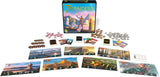 Boîte du jeu de société 7 Wonders avec illustration de cité antique, statue, phare et pyramide sur fond de ciel coloré.