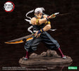Figurine de Tengen Uzui de Demon Slayer en pose de combat, tenant deux sabres, sur un socle rocheux. Il porte son bandeau orné de pierres précieuses et sa tenue de shinobi sans manches, mettant en valeur sa musculature.