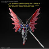 Maquette Gunpla HG 1/144 Destiny Gundam Spec II & Zeus Silhouette avec armement géant, ailes rouges et blanches sur fond blanc.