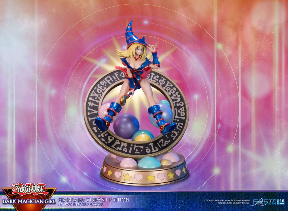 Figurine de Dark Magician Girl en PVC, posée dans un cercle magique décoré de runes, avec des sphères pastel à la base. Elle porte sa tenue bleue et rose emblématique, avec un chapeau pointu et une pose dynamique.