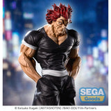 Figurine Baki Luminasta Yujiro Hanma par Sega, représentant Yujiro en tenue noire, mains dans les poches, cheveux rouges et posture menaçante sur un socle urbain.